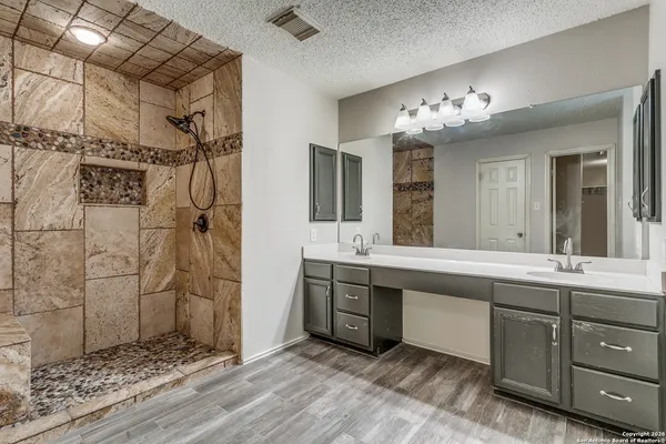 a spacious bathroom with a double vanity sink a large mirror and shower