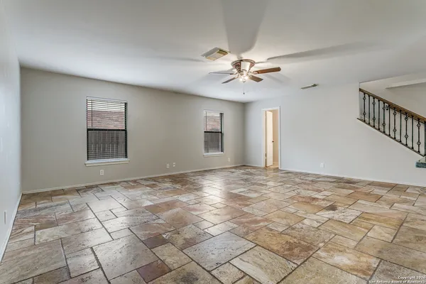 a view of an empty room with window and chandelier fan