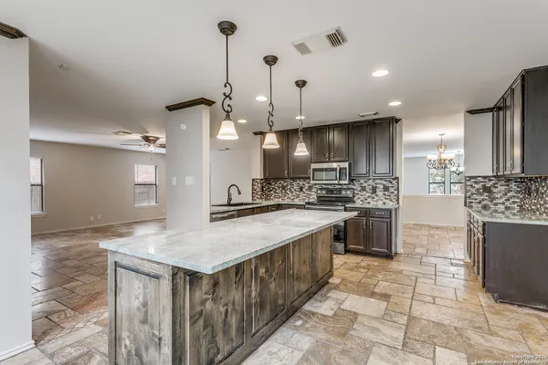 a kitchen with kitchen island a counter top space a sink stainless steel appliances and cabinets