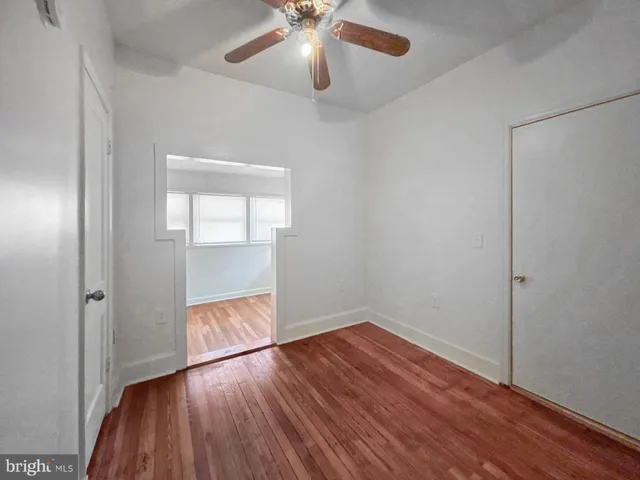 a view of empty room with wooden floor and fan