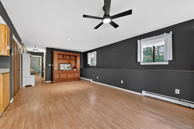 a view of an empty room with window and wooden floor