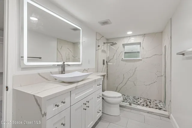 a bathroom with a granite countertop sink a toilet and shower