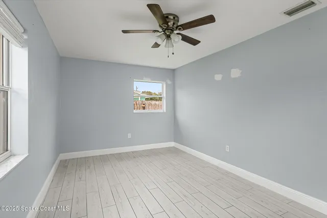 a view of an empty room with a window and a ceiling fan