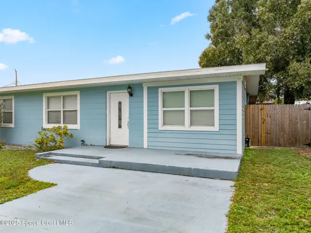 a view of a yard in front of a house with large trees
