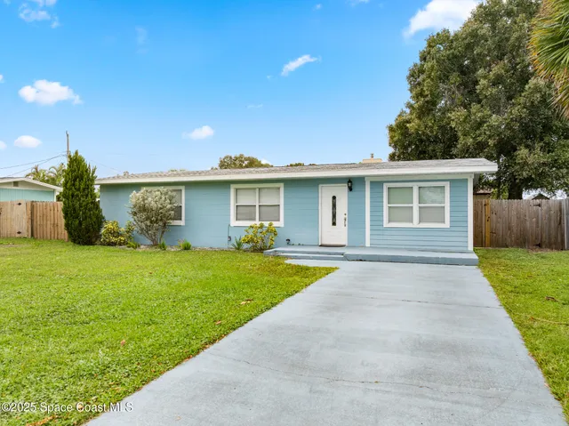 a view of a yard in front of a house with large trees