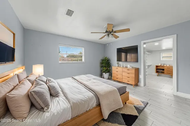 a spacious bedroom with a bed a mirror on dresser and a flat screen tv
