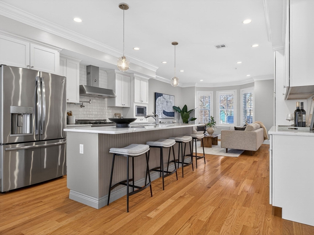 213 Lamartine Street, Unit 213A Boston, MA 02130 - Photo 3 of 39 a kitchen with stainless steel appliances granite countertop a refrigerator a stove top oven a sink dishwasher a dining table and chairs with wooden floor