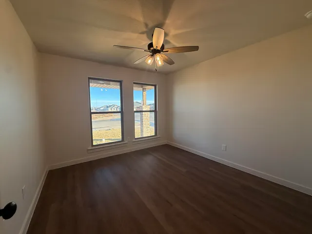 an empty room with wooden floor fan and windows