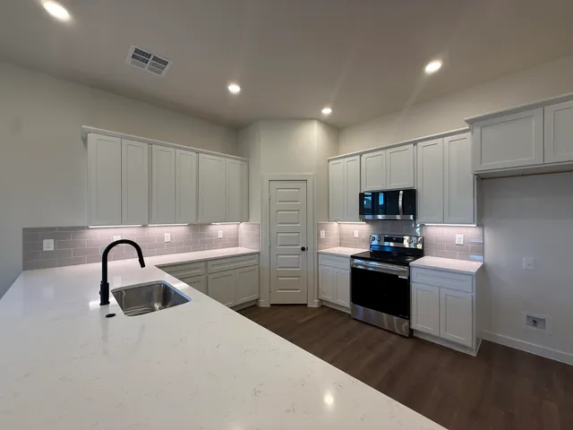 a kitchen with stainless steel appliances kitchen island a sink and a stove top oven with wooden floor