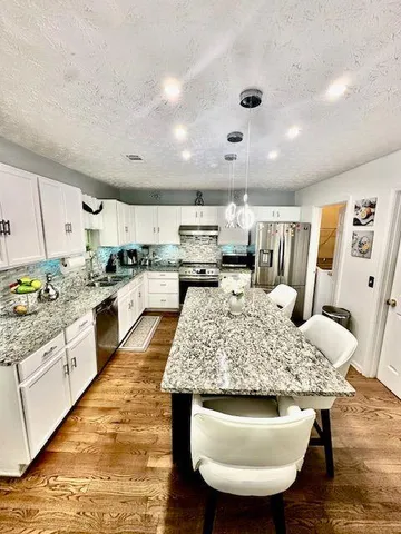 a kitchen with stainless steel appliances granite countertop a kitchen island a stove and a sink