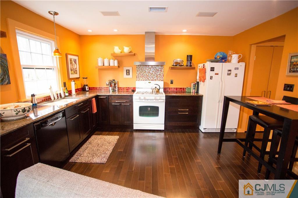 1301 Timber Oaks Road, Unit 1301 Edison, NJ 08820 - Photo 8 of 25 a kitchen with stainless steel appliances a stove a refrigerator a sink dishwasher and a dining table with wooden floor