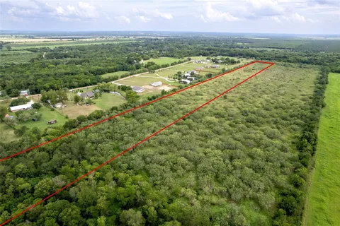 an aerial view of residential houses with outdoor space and trees