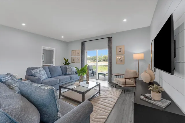 a living room with furniture a flat screen tv and a large window