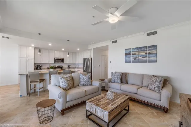 a living room with furniture kitchen view and a chandelier