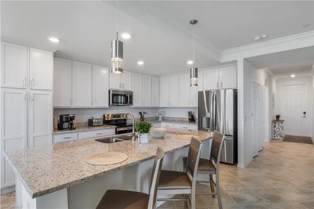 a kitchen with stainless steel appliances granite countertop a sink a stove a refrigerator with white cabinets and couches