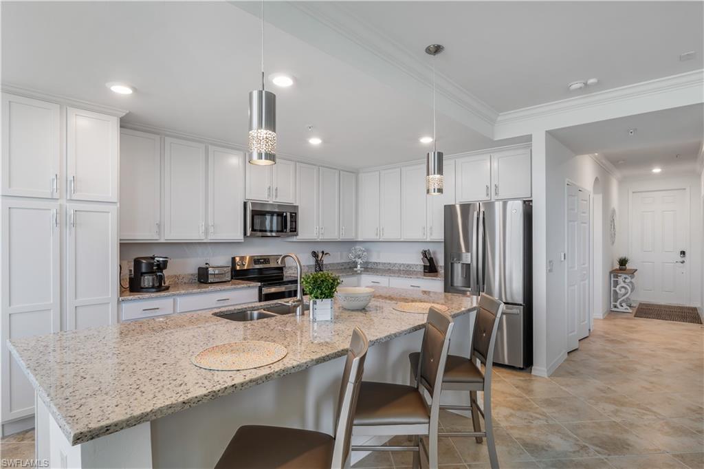43020 Greenway Boulevard, Unit 333 Babcock Ranch, FL 33982 - Photo 5 of 11 a kitchen with stainless steel appliances granite countertop a sink a stove a refrigerator with white cabinets and couches