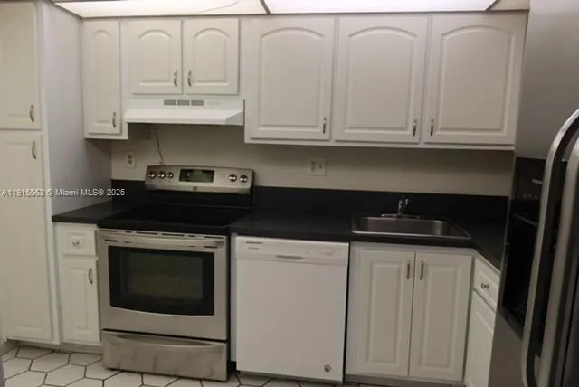 a kitchen with stainless steel appliances granite countertop white cabinets and a stove