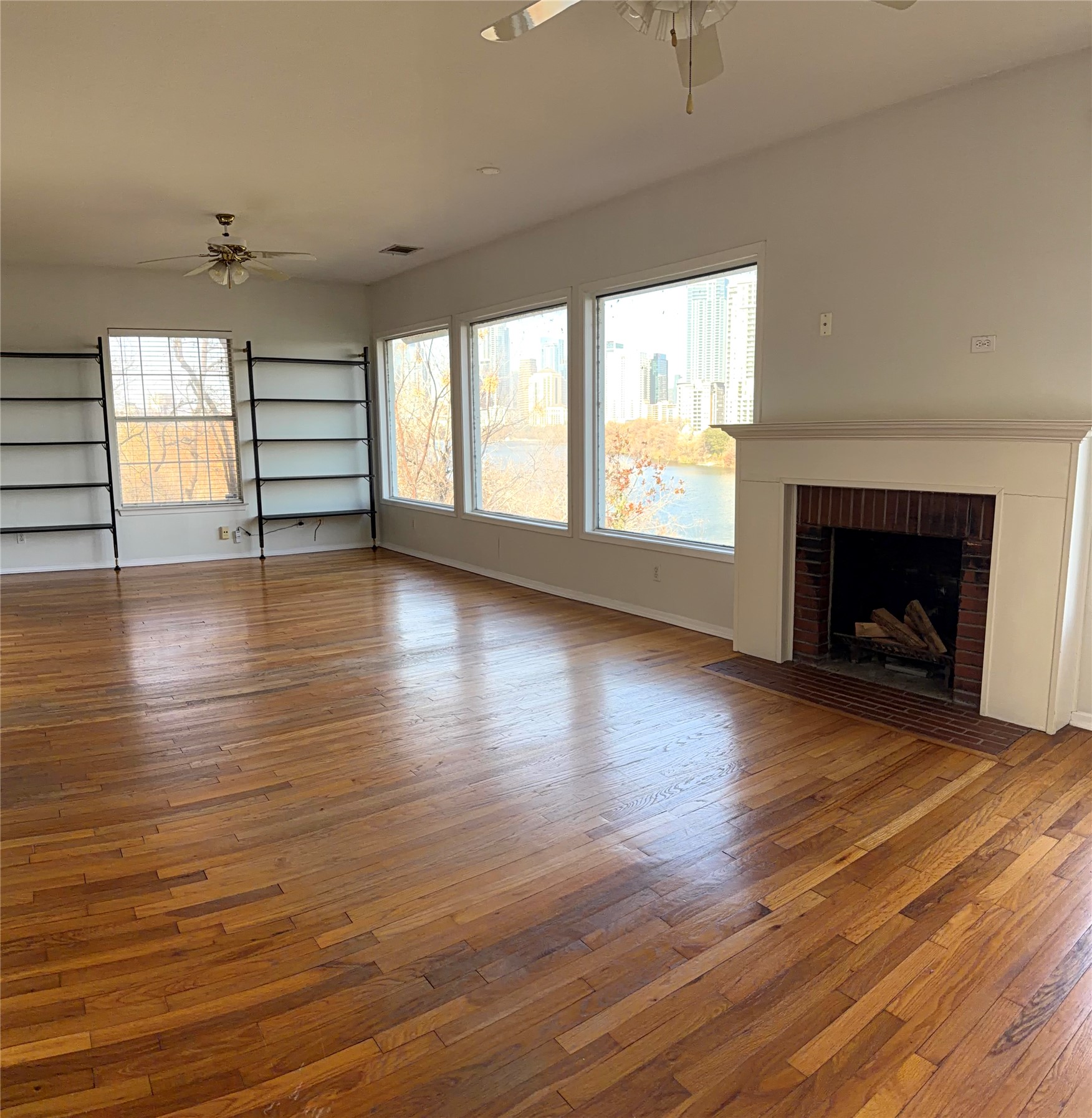 808 Edgecliff Terrace, Unit A Austin, TX 78704 - Photo 2 of 11 an empty room with wooden floor fireplace and windows
