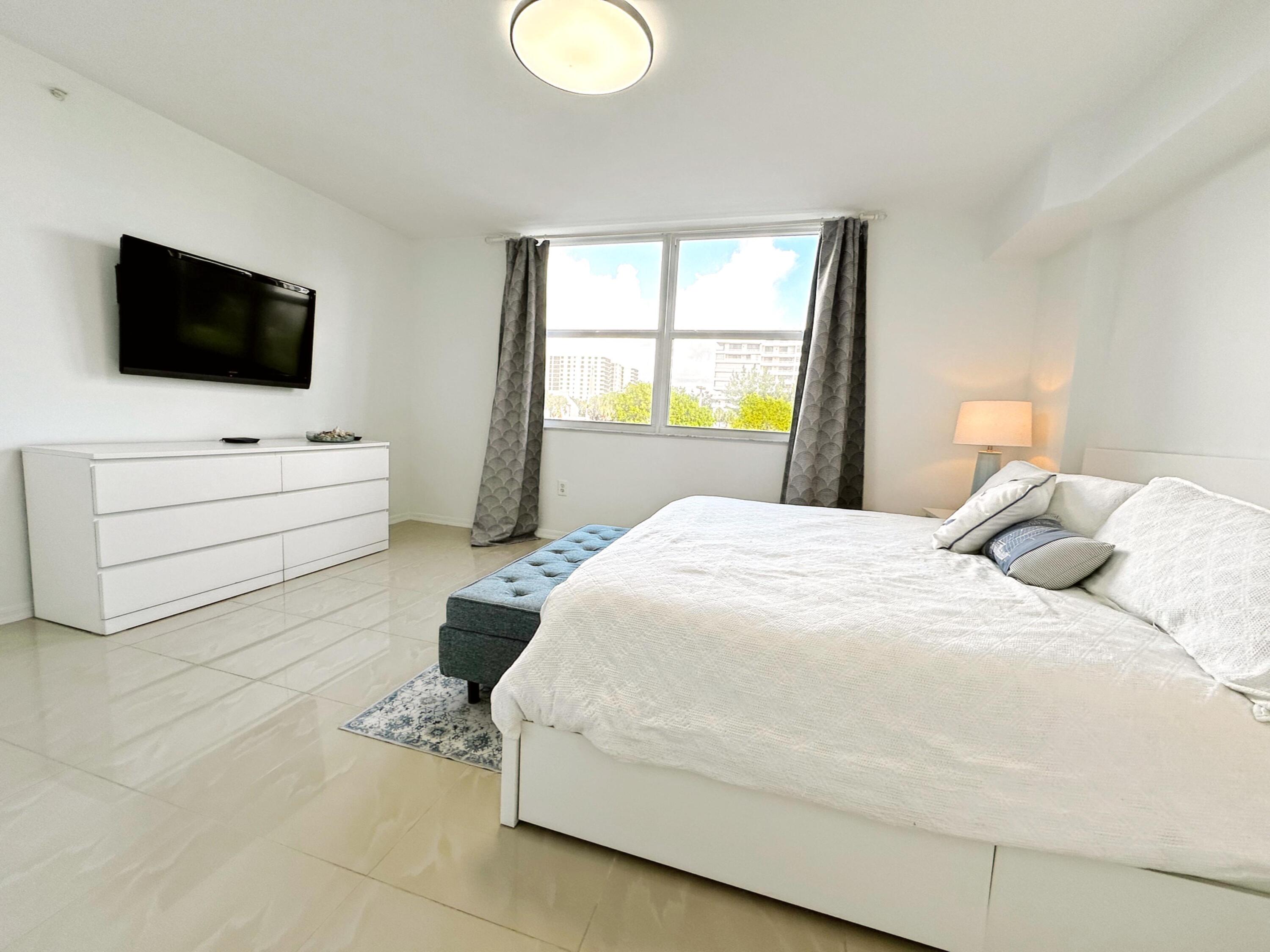 3594 South Ocean Boulevard, Unit 206 Highland Beach, FL 33487 - Photo 5 of 21 a bedroom with a bed a window and flat screen tv