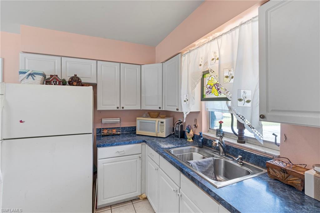 851 Barefoot Williams Road Naples, FL 34113 - Photo 13 of 35 a kitchen with a refrigerator sink and white cabinets