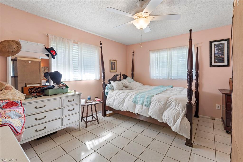 851 Barefoot Williams Road Naples, FL 34113 - Photo 15 of 35 a bedroom with a bed and a chandelier