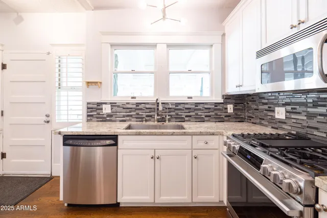 a kitchen with stainless steel appliances granite countertop a stove refrigerator and a window
