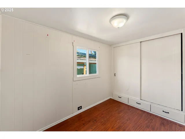 a view of an empty room with window and wooden floor