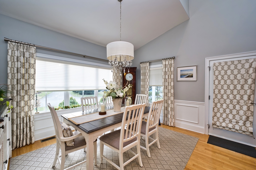 8 Hathaway Pond Circle, Unit 8 Rochester, MA 02770 - Photo 6 of 24 a dining room with wooden floor a chandelier a wooden table and chairs