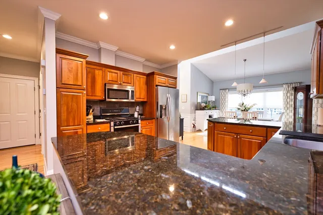 a large kitchen with stainless steel appliances kitchen island granite countertop a refrigerator and a stove top oven