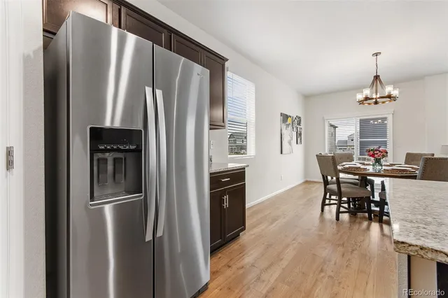 a kitchen with stainless steel appliances a refrigerator a stove a dining table and chairs with wooden floor