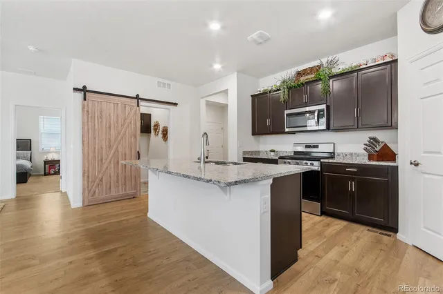 a kitchen with stainless steel appliances kitchen island granite countertop a refrigerator and a stove top oven