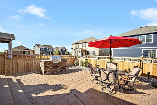 a view of a roof deck with table and chairs under an umbrella