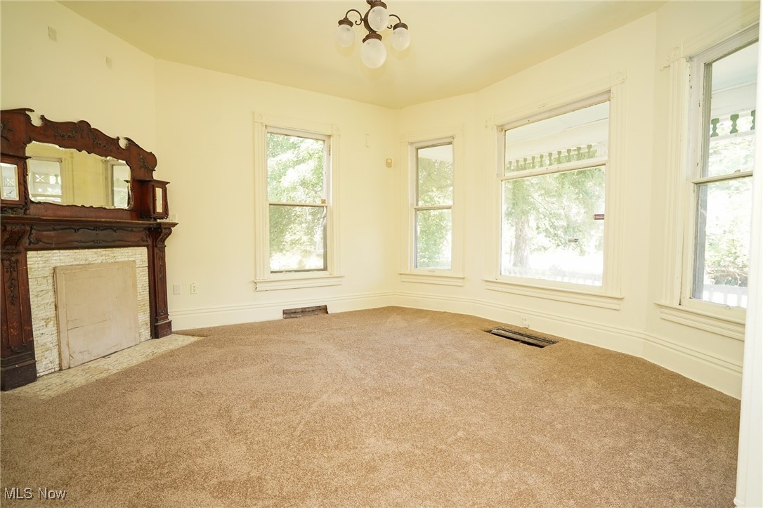1720 Jacobs Road Youngstown, OH 44505 - Photo 13 of 18 Unfurnished living room with carpet, a chandelier, and a stone fireplace