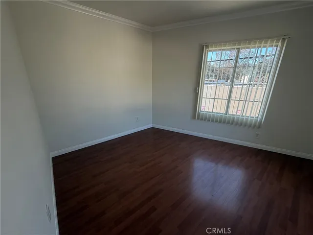 a view of an empty room with wooden floor and closet