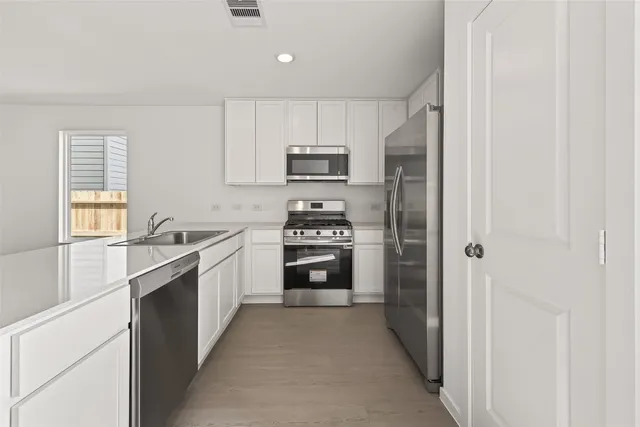 a kitchen with cabinets stainless steel appliances and a window
