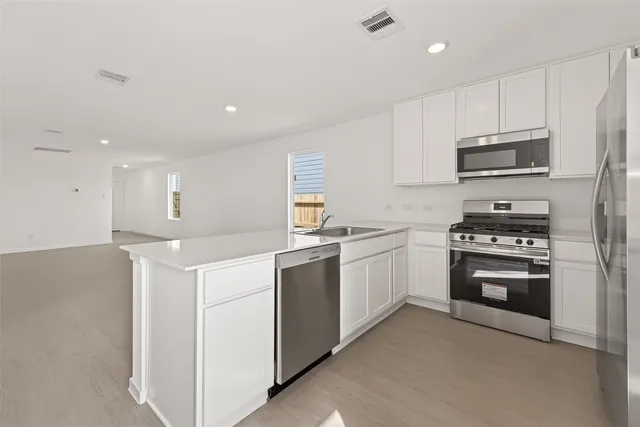 a kitchen with cabinets stainless steel appliances and sink