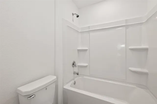 a white bath tub sitting next to a white toilet and vanity
