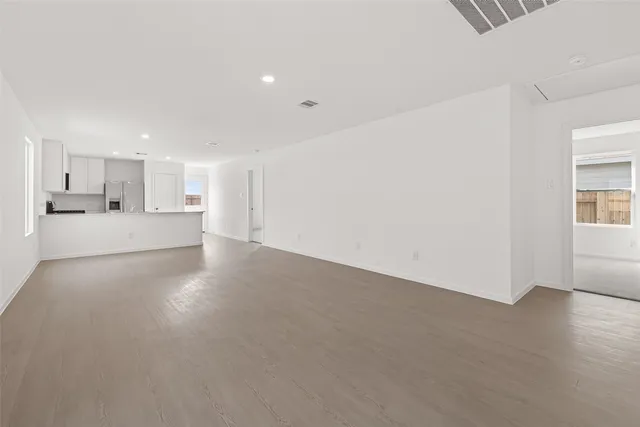 a view of an empty room with wooden floor and windows