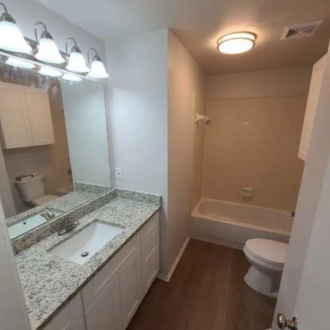 a bathroom with a granite countertop sink a toilet and bathtub