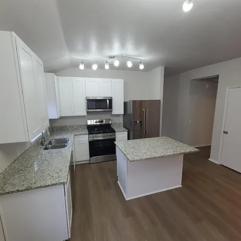 a kitchen with granite countertop stainless steel appliances a sink a stove top oven a counter space and cabinets