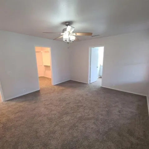 a view of an empty room with a chandelier fan