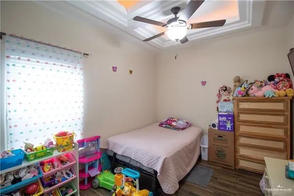 a bedroom with a bed a dresser and a chandelier