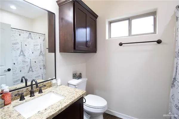 a bathroom with a granite countertop sink toilet a mirror and shower