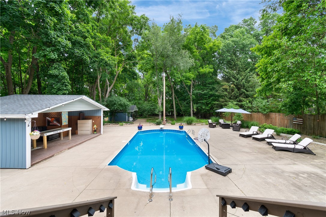 443 Merriman Road Akron, OH 44303 - Photo 2 of 44 In-ground swimming pool with concrete surround, featuring a dedicated pool house with a covered patio area