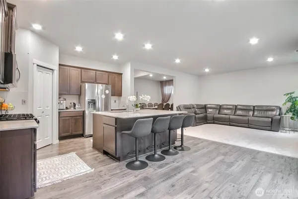 a kitchen with stainless steel appliances a refrigerator a sink dishwasher a oven and a dining table with wooden floor