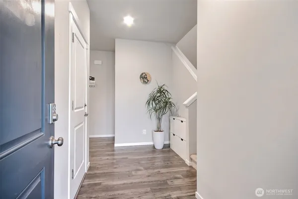 a view of a hallway with wooden floor and a bathroom