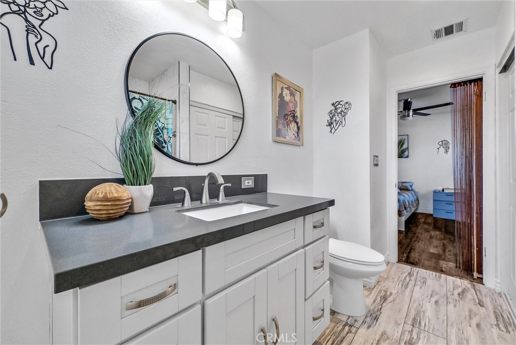 6220 Filkins Avenue Rancho Cucamonga, CA 91737 - Photo 28 of 37 a bathroom with a granite countertop toilet a sink and a mirror