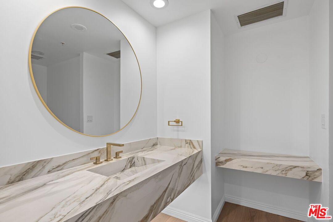 10490 Wilshire Boulevard, Unit 1004 Los Angeles, CA 90024 - Photo 23 of 45 a bathroom with a granite countertop sink and a mirror