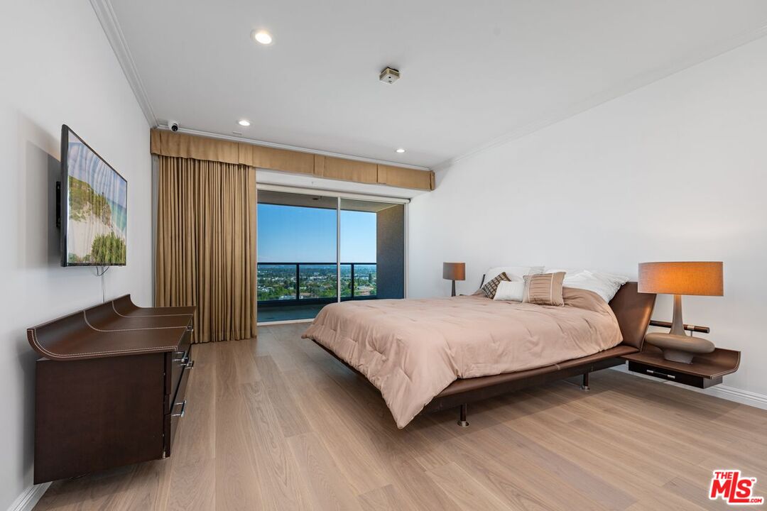 10490 Wilshire Boulevard, Unit 1004 Los Angeles, CA 90024 - Photo 24 of 45 a bedroom with a bed and a flat tv screen on a dresser