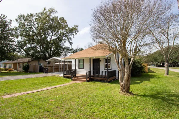 a view of a house with a big yard and large trees